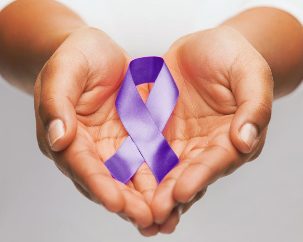 Close up of a woman's cupped hands holding a purple ribbon for Domestic Violence Awareness Month